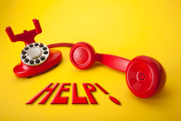 istock Retro red telephone on a yellow background with the word help above it 2203303329