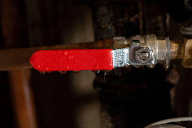 istock Red lever handle on metal pipe with water droplets in industrial setting 2203304951
