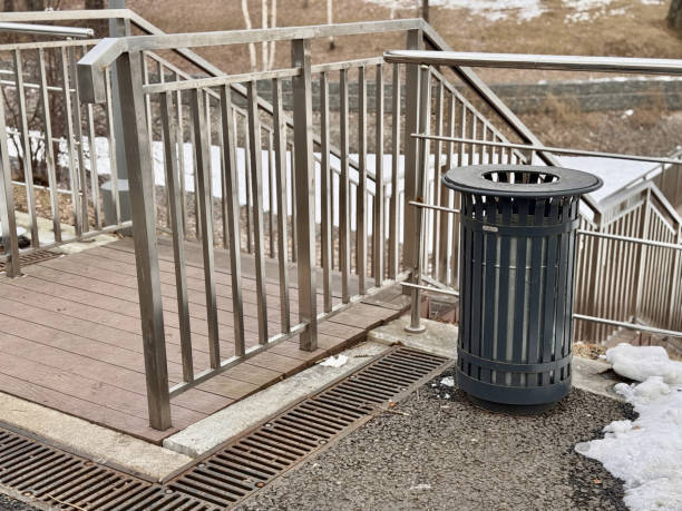 istock A metal trash bin is situated within an outdoor urban environment that is surrounded by a fresh snowfall. The Urban Trash Bin in Public Spaces is vital for community cleanliness and waste efficiency 2203306536