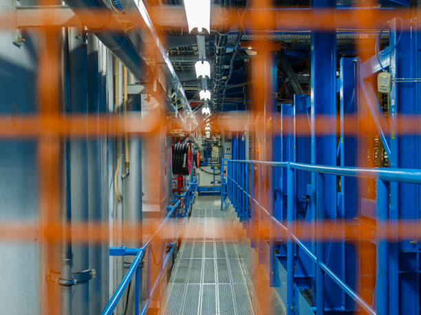 Geneva, Switzerland - February 5, 2025: Industrial corridor with safety barrier, grating, pipes, and coiled wires.