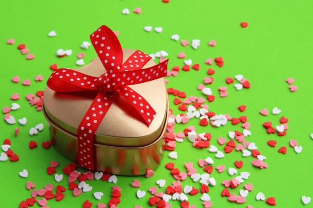 Golden heart-shaped container with red ribbon bow on colorful hearts