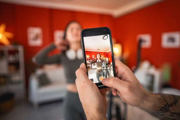 istock man filming woman with mobile phone while she show exercise at home 2203317827