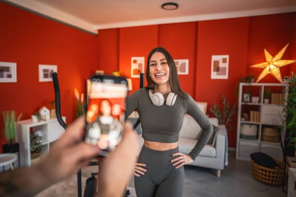 man filming woman with mobile phone while she exercise and show exercises at home