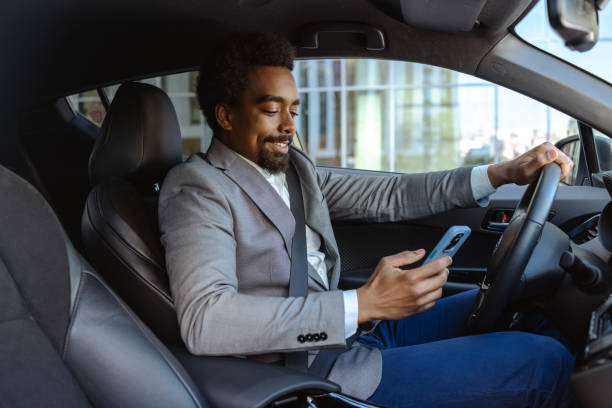 istock Man in formal attire using a phone while seated in a car 2203319816