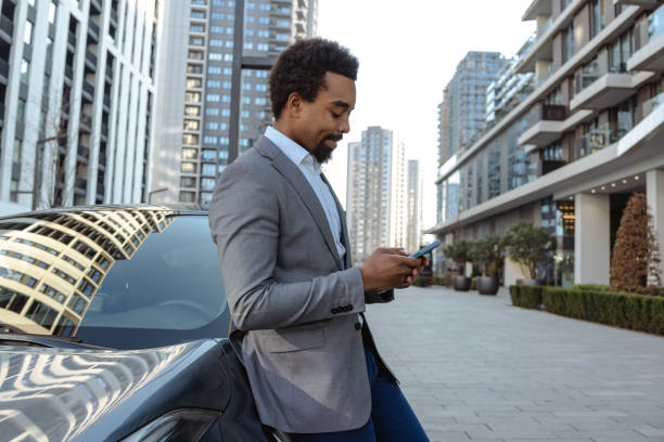 istock Professional man using smartphone outdoors near vehicle in urban setting 2203319904