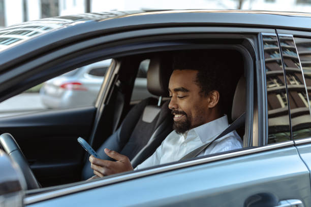 istock Man in car using smartphone while smiling and sitting comfortably in his car 2203320972