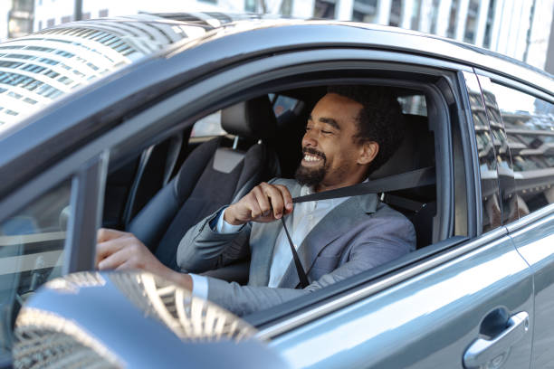 istock Man fastening seatbelt inside a modern vehicle smiling confidently 2203321089