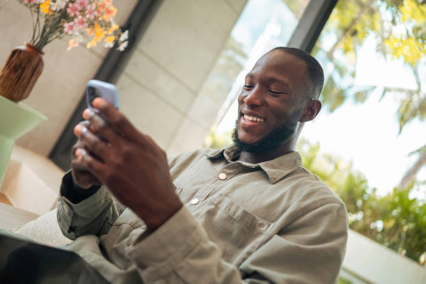 istock Smiling Black Man with Smartphone and Tablet on Sofa 2203331340
