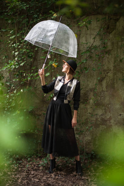 istock Young woman holding transparent umbrella, while standing and  checking the rain. 2203332085