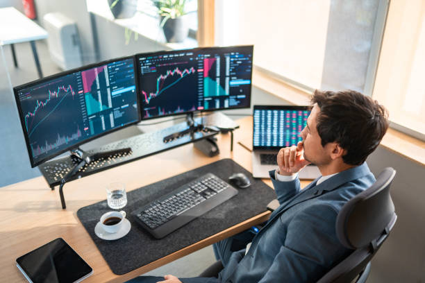 Mid Adult Asian Stockbroker Analyzing Financial Data on Monitors