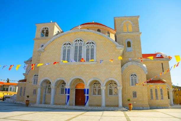 Cathedral of Saint Barnabas and Saint Makarios in Nicosia, Cyprus. Ornate church with multiple arched windows and doorways, decorated with colorful flags and banners, under a clear blue sky