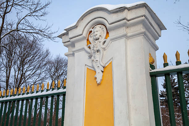 A beautifully detailed fence post featuring intricate sculptures and a vibrant design, captured during winter in a snowy landscape, evoking a sense of elegance and timeless architecture. St Petersburg