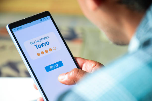 istock Man using mobile applications to book guided tour to explore Tokyo city. Vacation planning using concepts, digital display with rating. 2203339258