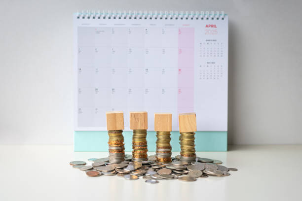 istock Four toy blocks in a row on top of coins. 2203341329