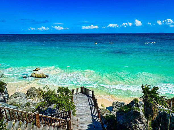 Brilliant blue green waters of the warm Caribbean sea with a viewing deck leading to the sandy beach at the  late 13th century Mayan ruins of Tulum,Mexico