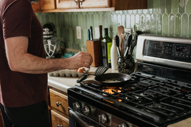 istock Man melts butter on a pan in a kitchen to cook eggs for breakfast 2203342377
