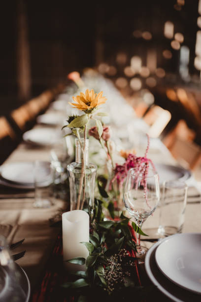 istock Close up of wedding reception table in rustic barn with flowers 2203347110