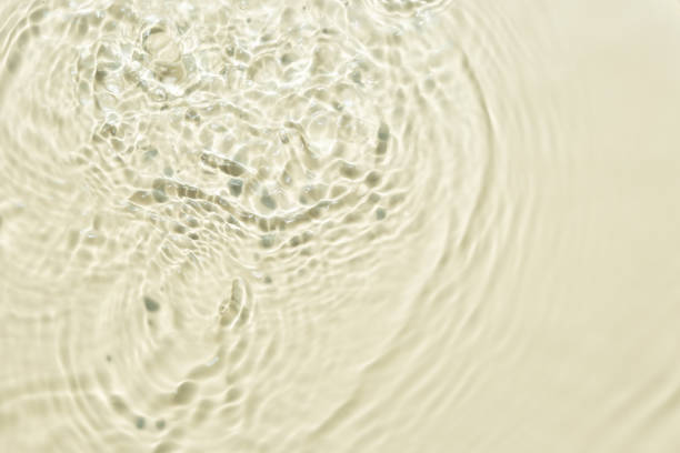 Top view background summer natural Beige surface, clear water with ripples and splashes. water waves in sunlight The water surface has waves and concept background cosmetics moisturizer toner