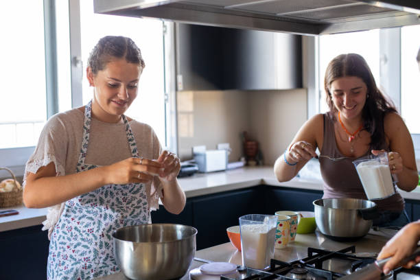 istock Happy young female friends preparing a cake in the kitchen 2203351865