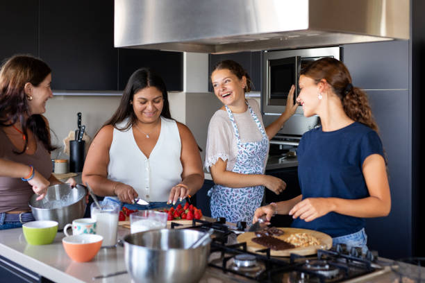 istock Happy young female friends preparing a cake in the kitchen 2203351920