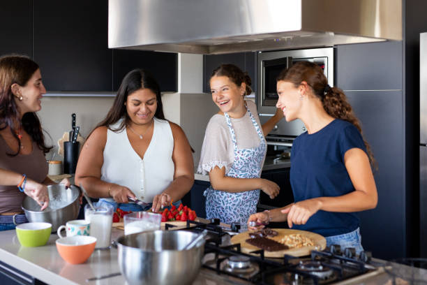 istock Happy young female friends preparing a cake in the kitchen 2203351924