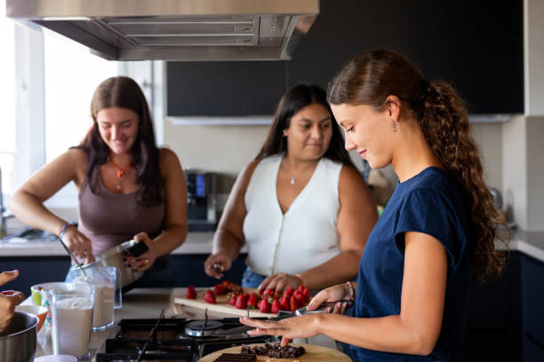 istock Happy young female friends preparing a cake in the kitchen 2203351952