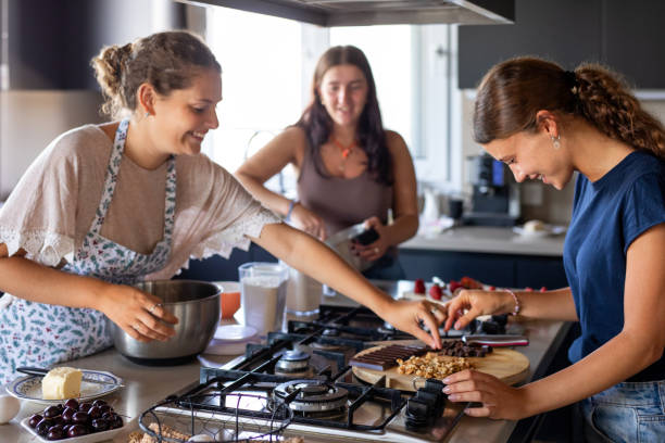 istock Happy young female friends preparing a cake in the kitchen 2203351955