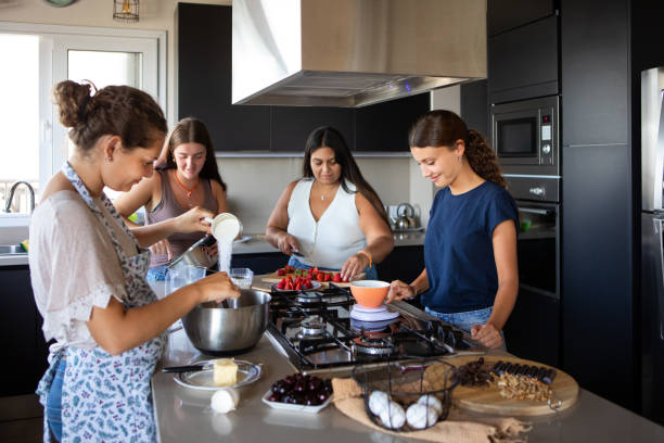 istock Happy young female friends preparing a cake in the kitchen 2203351984