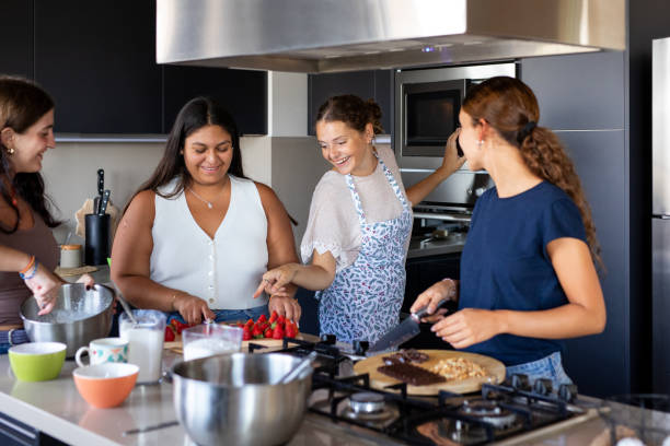 istock Happy young female friends preparing a cake in the kitchen 2203352033