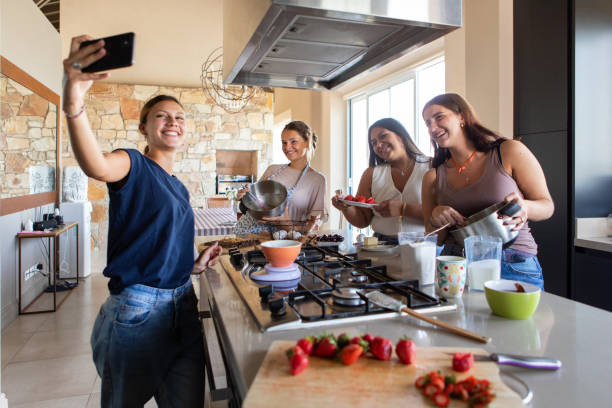 Happy young female friends preparing a cake in the kitchen