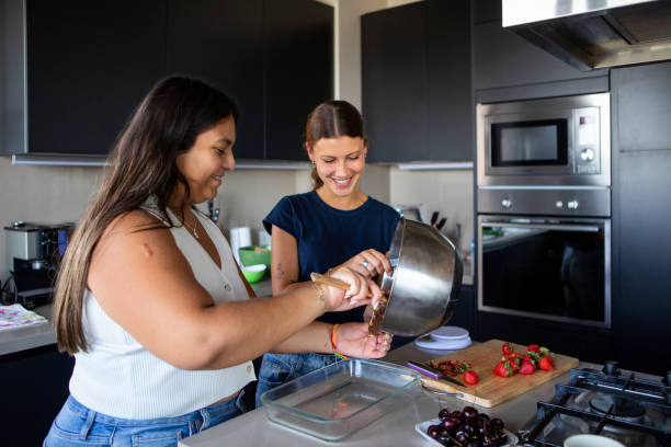 istock Happy young female friends preparing a cake in the kitchen 2203352123