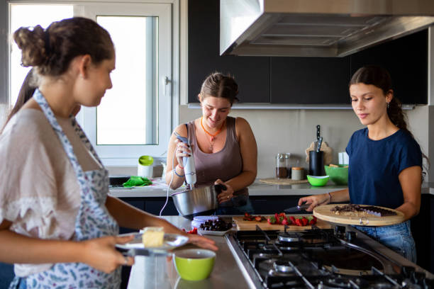 istock Happy young female friends preparing a cake in the kitchen 2203352403