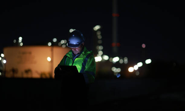istock A chemical engineer is checking equipment and discussing work using a walkie-talkie at an oil refinery at night. A chemical engineer is inspecting machinery and talking about their work using a walkie-talkie at an oil refinery during the night. 2203352951