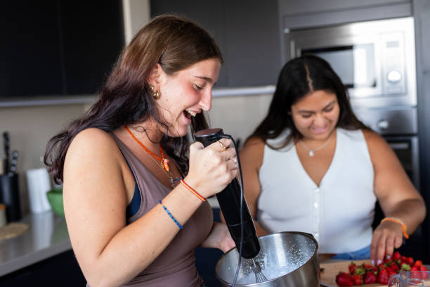 istock Happy young female friends preparing a cake in the kitchen 2203354041