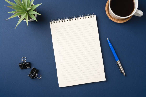 istock Top view of a workspace with a blank notebook, pen, coffee, and plant 2203361925