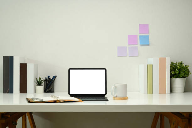 istock Digital tablet with a blank screen, leather planner and a cup of coffee on white table. 2203363065