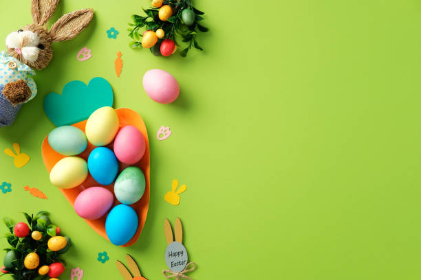 istock Happy Easter concept. Flat lay colorful Easter eggs in a carrot-shaped tray with festive decorations and bunny toy on a green background. 2203363527