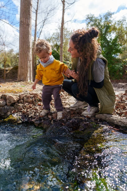 istock Mother and son exploring nature near a small river in a forest 2203364826