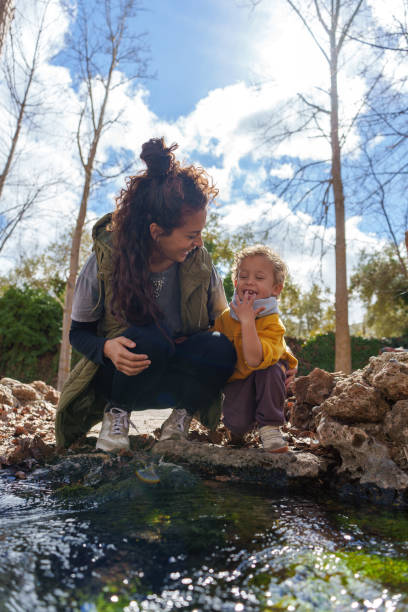 istock Mother and son exploring nature by a stream in a nature reserve 2203364858