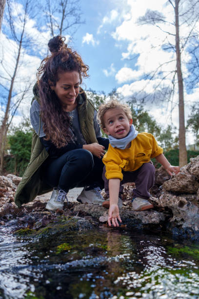 istock Mother and son exploring nature touching water in a creek 2203364859