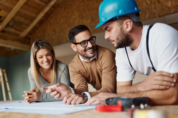 istock Happy couple talking to manual worker at construction site. 2203364946