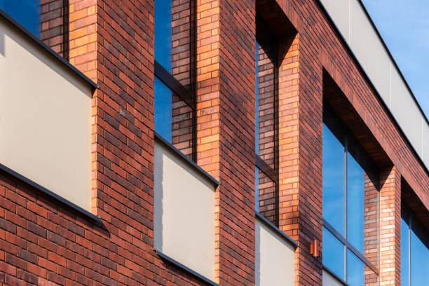 A detailed close-up of a contemporary red brick building with large reflective windows, showcasing modern architectural design.