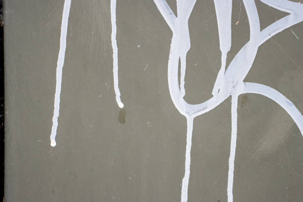 Dripping White paint spread unevenly on a black wall.