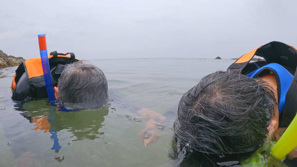 Closeup asian elderly couple is snorkeling head in the water - they have courage to try new things with personality unrestricted