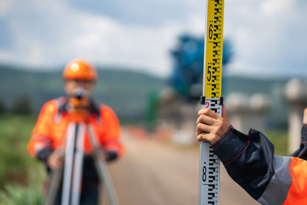 istock Survey team is working with a theodolite and road construction plans. Civil engineers are taking measurements with surveying tools during the construction. 2203368948