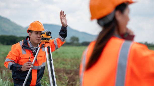 istock Survey team is working with a theodolite and road construction plans. Civil engineers are taking measurements with surveying tools during the construction. 2203369131