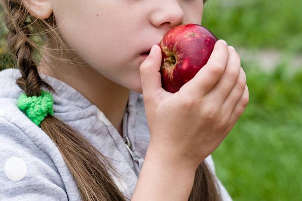 istock Child eating a red apple outdoors 2203369247