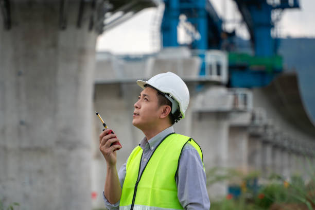 istock Construction worker in a yellow vest is holding a walkie talkie 2203369929