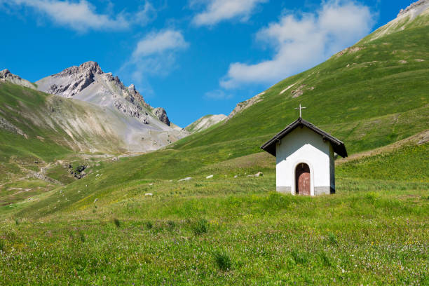 Small chapel on the green alpine meadow as mountains on background near Colle della Maddalena mountain pass on France - Italy border.