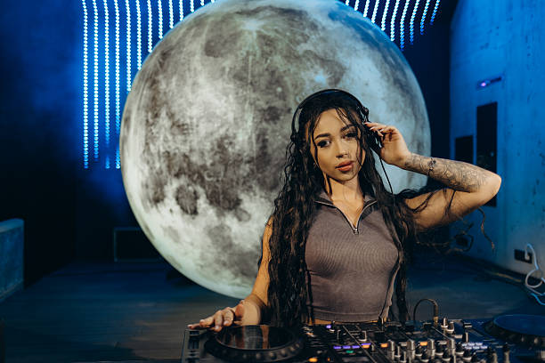 istock Female DJ Performing in a Club with a Moon-Themed Backdrop 2203370749